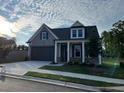 Charming home with gray siding, a covered porch with stone supports, and a two-car garage at 1209 Lakeside Overlook, Canton, GA 30114