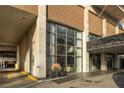 Building entrance with large windows, visible street sign, and landscaped pots at 620 Peachtree Ne St # 502, Atlanta, GA 30308