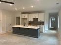 Open-concept kitchen with large island, white cabinets, stylish gray backsplash, and modern finishes at 420 Carrera Ln, Acworth, GA 30102