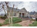 A quaint one-story home with tan siding, brick accents, a cozy front porch, and mature landscaping at 950 Brook Knoll Ln, Cumming, GA 30041