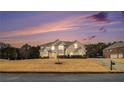Inviting two-story brick home with mature trees, lush landscaping, and a beautiful sunset backdrop at 15 Sugarmaple Ct, Oxford, GA 30054