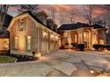 Elegant brick home at dusk featuring a circular driveway, three-car garage, and beautiful exterior lighting at 150 Stone Pond Ln, Johns Creek, GA 30022