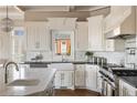 Beautiful kitchen featuring marble backsplash, white cabinetry, stainless steel range, and a farmhouse sink at 6955 Laurel Oak Dr, Suwanee, GA 30024