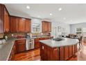 Open kitchen featuring stainless steel appliances, dark wood cabinets, and an island with gas cooktop at 4450 Sandalwood Way, Cumming, GA 30041