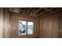An unfinished bedroom with exposed framework, two windows and a view of the neighboring home at 2017 Ripple Park Bend, Canton, GA 30114