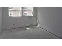 Unfinished bedroom with bare white walls, concrete floors, and natural light from two large windows at 2017 Ripple Park Bnd, Canton, GA 30114