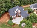Aerial view of a brick two-story home with mature landscaping, a large driveway, and a two-car garage at 1258 Mcallistar Dr, Locust Grove, GA 30248