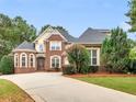 Charming two-story brick home featuring a manicured lawn, mature trees, and a wide driveway at 1258 Mcallistar Dr, Locust Grove, GA 30248