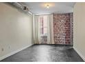 Bright living room features exposed brick wall, large window with bright natural light, and concrete flooring at 800 Peachtree Ne St # 8508, Atlanta, GA 30308