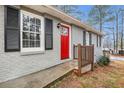 Close-up of the gray brick home's front entrance, featuring a bright red door with decorative glass at 3005 Hidden Dr, Lawrenceville, GA 30044