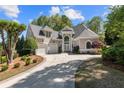 Beautiful two-story home with a well-manicured lawn, lush landscaping, and a circular driveway at 1002 Wetherby Way, Johns Creek, GA 30022