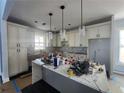 Well-lit kitchen with white cabinets, marble counters, and modern pendant lighting at 1064 Eastview Ne Rd, Conyers, GA 30012