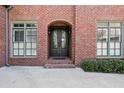 The brick home features a secured glass front door and flanking windows with white shutters at 29 Cliftwood Dr, Sandy Springs, GA 30328