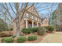 A stately brick home with mature landscaping, a columned porch, and an attached garage at 1085 Highland Crest Ct, Mableton, GA 30126