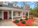 Inviting front porch with red mulch landscaping, and stone accents, perfect for relaxing outdoors at 10 Oakbrook Ln, Covington, GA 30016