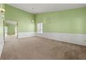 Spacious living room with light green walls, wall trim, and neutral carpet at 3296 Quincey Xing, Conyers, GA 30013