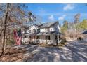 Inviting two-story home with a wraparound porch, American flag, and a spacious driveway, perfect for a Gathering at 1700 Bailey Creek Sw Rd, Conyers, GA 30094