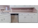 Close-up of the kitchen featuring stainless steel dishwasher and white cabinetry at 1070 Thornwood Cir, Covington, GA 30016