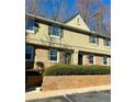 Beautiful townhome exterior featuring a brick base, upper level windows, and a manicured green hedge at 6900 Roswell Rd # 7N, Atlanta, GA 30328