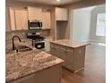 Well-lit kitchen boasts stainless steel appliances, granite countertops, and a convenient center island at 117 Legends Way, Hiram, GA 30141