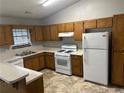 Traditional kitchen showcasing wood cabinets, white appliances, and a functional layout at 1281 Bugle Ct, Hampton, GA 30228