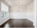 Bright dining room features dark hardwood floors, wainscoting, and modern chandelier at 5995 Spring Way, Stonecrest, GA 30038
