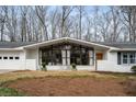 The home's front exterior features painted white brick and a wall of picture windows, bringing the outside in at 665 Lake Charles Way, Roswell, GA 30075
