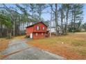 Red two-story home featuring a long driveway and charming stone-accented front porch on a wooded lot at 1057 Forest Path, Stone Mountain, GA 30088