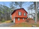 Side view of red two-story home showing attached garage, dark shutters, and a tree-filled lot at 1057 Forest Path, Stone Mountain, GA 30088