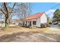 Quaint cottage-style home featuring a red roof, inviting front porch, and a spacious yard at 204 Emory St, Oxford, GA 30054