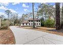 View of a two-story home with light-colored brick, brown shutters, manicured landscaping and a long driveway at 743 Cedar Sw Trce, Lilburn, GA 30047