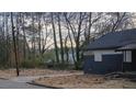 Compact single-level home with a dark exterior and adjacent driveway nestled amongst mature trees at 516 Warren Ave, Scottdale, GA 30079