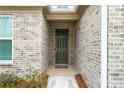 Inviting entryway featuring a brick facade, covered porch, and a dark green front door at 6451 Crest Brook Way, Buford, GA 30518