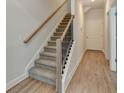 A staircase with carpeted treads, white risers, and a stained wood handrail at 5477 Blossomwood Sw Trl, Mableton, GA 30126