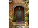 A beautifully crafted arched front door, flanked by manicured topiaries, welcomes you to this inviting home at 10594 Serenbe Ln, Chattahoochee Hills, GA 30268