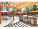 Community outdoor grilling area with pergola, stone countertop, stainless grill, and picnic tables at 795 Hammond Dr # 1712, Atlanta, GA 30328