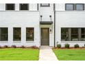 Close up view of townhome featuring white brick, dark trim, and well manicured lawn leading to the front door at 1322 Parc Bench Rd, Atlanta, GA 30316