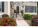 Close-up of a welcoming front entrance with stone steps and a manicured landscape featuring vibrant red and pink azaleas at 4651 Oakleigh Manor Dr, Powder Springs, GA 30127