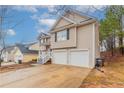 View of the two car garage, driveway, and landscaping on this cozy two-story home at 6557 Snow Bird Ln, Douglasville, GA 30134
