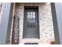 Close-up of a gray front door with glass inset and a 'Home Sweet Home' sign at 1430 Baygreen Rd, Suwanee, GA 30024