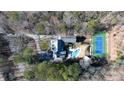 An aerial shot showcases the home, in-ground pool, tennis court, and surrounding wooded property at 4000 Conway Valley Nw Rd, Atlanta, GA 30327