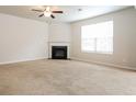 Spacious living room featuring plush carpeting, a ceiling fan, and a cozy fireplace at 4924 Rapahoe Trl, Atlanta, GA 30349