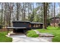 View of contemporary home with dark siding, carport, stone walkway, and natural landscaping at 3637 Eaglerock Dr, Atlanta, GA 30340