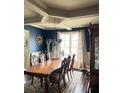 Spacious dining room featuring a long wooden table, decorative mirror, and window with patterned curtains at 3740 Tupelo Trl, Auburn, GA 30011