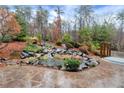 An outdoor patio features a scenic pond with natural rock waterfall and professionally landscaped trees and shrubs at 2691 Jamerson Rd, Marietta, GA 30066
