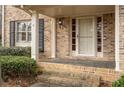 Inviting front porch with brick steps and pillars leading to a classic white front door with black shutters at 1958 Starfire Ne Dr, Atlanta, GA 30345