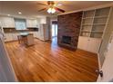 Spacious living room featuring hardwood floors, a brick fireplace, built-in shelves, and natural light from a large window at 6542 Cherry Tree Ln, Atlanta, GA 30328