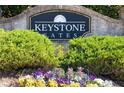 Keystone Gates signage surrounded by vibrant flowers and lush greenery, showcasing a welcoming entrance at 2613 Stonekey Bnd, Lithonia, GA 30058