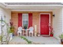 Cozy front porch with red door, brick accents, and a welcoming seating area at 5555 Sugar Crossing Dr, Sugar Hill, GA 30518