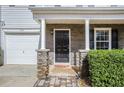 Close-up of the front porch with stone accents, black front door, and neatly trimmed hedges at 5545 Mountain Top Pl, Cumming, GA 30041